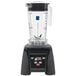 A black Waring commercial blender with a clear container.