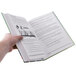 A close-up of a hand holding an open book with a white background.