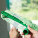 A close-up of a person's hand holding a green Unger strip washer.