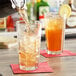 A person pouring liquid into an Anchor Hocking Clarisse cooler glass on a table.