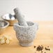 A Fox Run granite mortar and pestle with garlic and peppercorns.