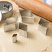 A metal container with Ateco stainless steel diamond-shaped cookie cutters and a rolling pin.