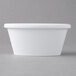 A Carlisle white melamine oval ramekin on a gray surface.