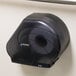 A black San Jamar Reserva Oceans jumbo toilet paper dispenser on a wall.