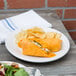 A White Fiesta luncheon plate with a burrito and chips on a table.