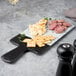 a black serving board with crackers on it