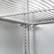 A metal shelf with metal hooks on a metal wall.