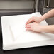 A person's hands on a stack of Hoffmaster white flat pack linen-feel napkins.