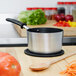 A Vollrath Wear-Ever sauce pan with a wooden spoon on a counter.