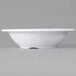 A white Carlisle melamine bowl on a gray surface.