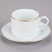 a white cup with gold rim and a saucer