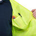 A man wearing a Cordova Lime high visibility safety vest holding a tool in the pocket.