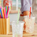 A person holding a plastic cup with a straw filled with ice.