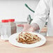 A chef holding a plate of French fries cut with a Choice Prep French Fry Cutter.