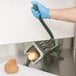 A person wearing blue gloves uses a Choice Prep 3/8" French Fry Cutter to cut potatoes.