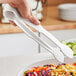 A person using Thunder Group white polycarbonate tongs to serve a salad.