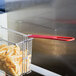 A Cecilware fryer basket with food in it, held by a red handle.