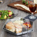 A Genpak clear plastic hexagonal lid with a sandwich, salad, and drink in a container on a table.