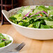 A close-up of a bowl of salad with a fork and knife in it.