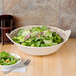 A bowl of salad with lettuce and purple cabbage in a GET Olympia melamine bowl on a table.