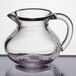 A clear plastic creamer with a handle.