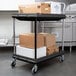 A black Metro utility cart with white boxes on the shelves.