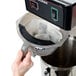 A hand placing a Bigelow iced tea filter bag into a plastic container.