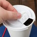 A hand opening a coffee cup with a white Solo plastic lid.