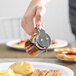 A person using a Tablecraft glass syrup dispenser to pour syrup on a plate of food.