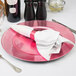 A Tabletop Classics pink plastic charger plate on a white background with a fork and spoon.