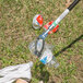 A person using an Unger NiftyNabber Pro to pick up a plastic bottle near a trash can.