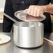 A person using a Vollrath Wear-Ever Classic Select aluminum sauce pan lid over a pot.