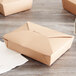 A group of brown Fold-Pak Bio-Plus-Earth paper take-out boxes on a table.