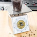 An Edlund Four Star series portion scale with a plastic container of coffee beans on top.