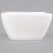 A white square porcelain ramekin with a black handle.