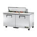 A True refrigerated sandwich prep table with food on top.