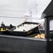 A chef is preparing food in a Carlisle portable salad bar on a counter in an outdoor catering setup.