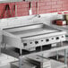 A large stainless steel countertop griddle with manual controls, designed for commercial kitchen use.