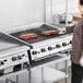 A commercial Garland GTBG36-AR36 natural gas radiant charbroiler with adjustable grates being used to grill meat in a professional kitchen.