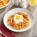 An Acopa bright white stoneware plate with breakfast food on a table.