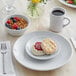 A plate of food with a biscuit on it and a cup of coffee on a white surface.