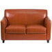 A brown leather loveseat with wooden legs.