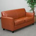 A brown leather loveseat in a lounge area.