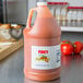 A gallon jug of Firey Louisiana hot sauce on a counter.