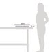 A woman standing next to a table with a white rectangular GET Melamine food pan on it.