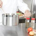 A chef stirring food in a Vollrath stainless steel sauce pan.