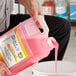 A man pouring pink Noble Chemical All Surf liquid into a white bucket.