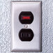 A close-up of a metal wall switch with red and black numbers on a Kolpak walk-in cooler.