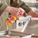 A person spraying Vegalene All Purpose Liquid Release onto a metal tray.