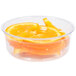 A Fabri-Kal clear plastic deli container filled with orange slices on a counter.